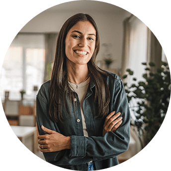 Smiling woman standing with arms crossed indoors.